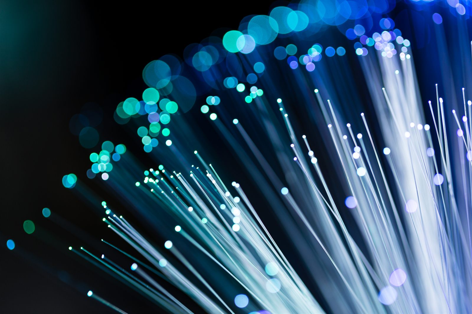 Macro view of fibre optic strands carrying blue and green light against a dark background